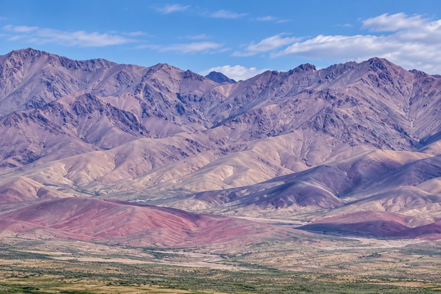 蓝天下层叠的紫灰色群山与山前草地（AI生成意境图）